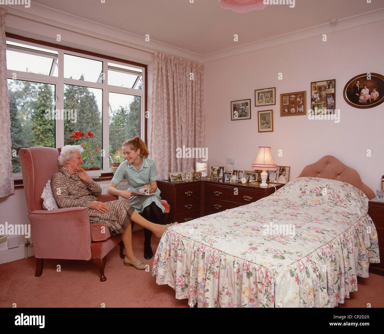 Resident with nurse in bedroom in nursing home, Surrey, England, United Kingdom Stock Photo