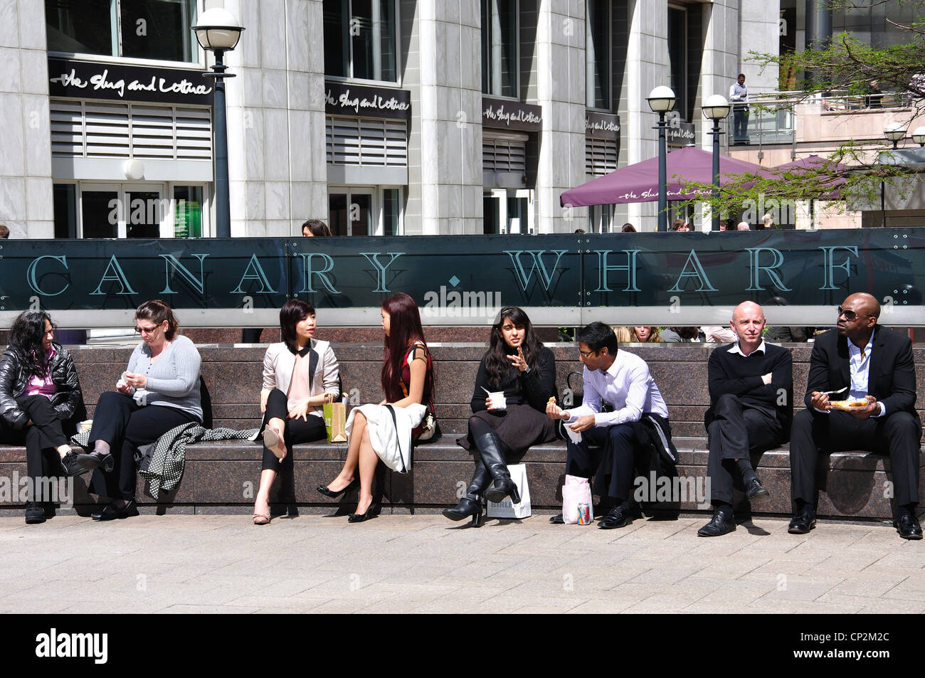Workers at lunchtime sitting in Reuters Plaza, Canary Wharf, London Borough of Tower Hamlets, London, England, United Kingdom Stock Photo