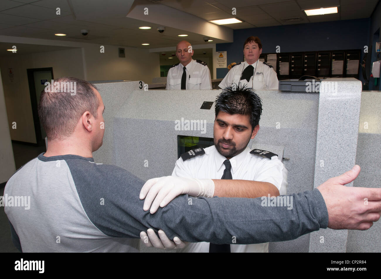 Suspect being searched at charge desk in a police station Stock Photo