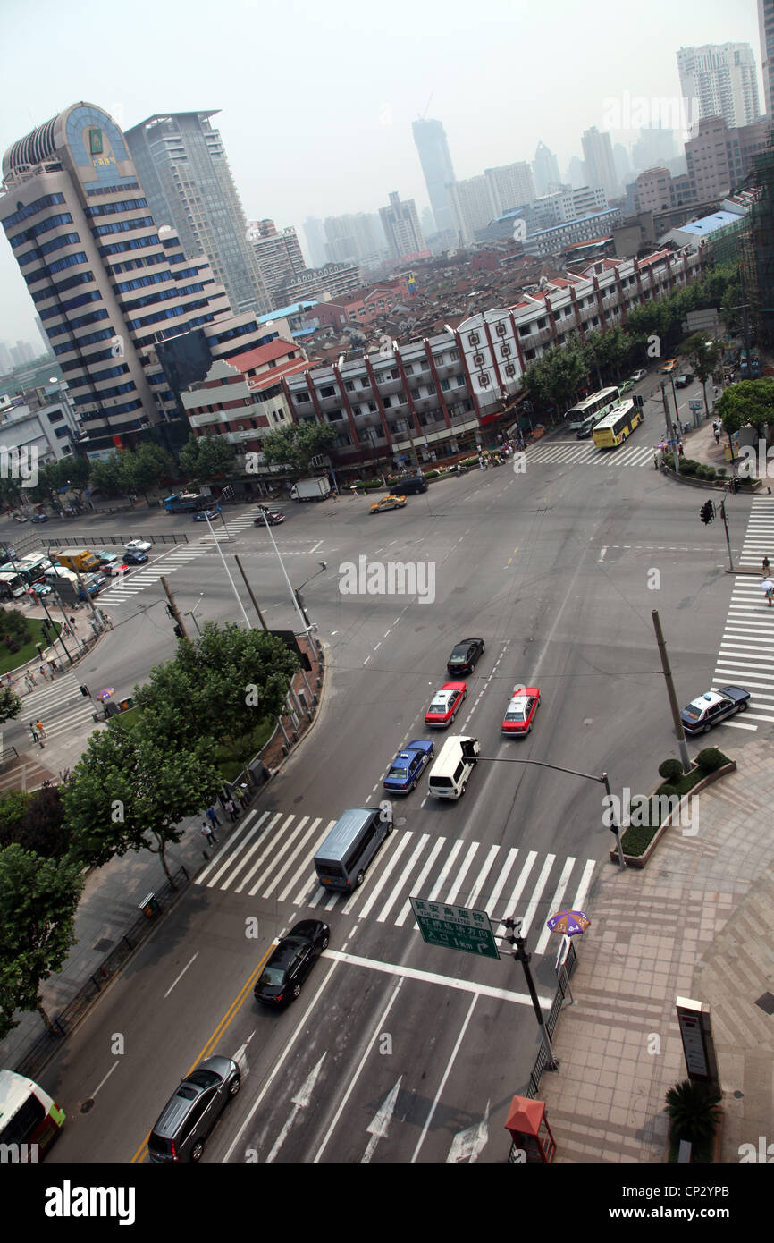 It' a crossroad in Shanghai. We can see some cars waiting at the traffic lights ans some typical houses in the background. Stock Photo