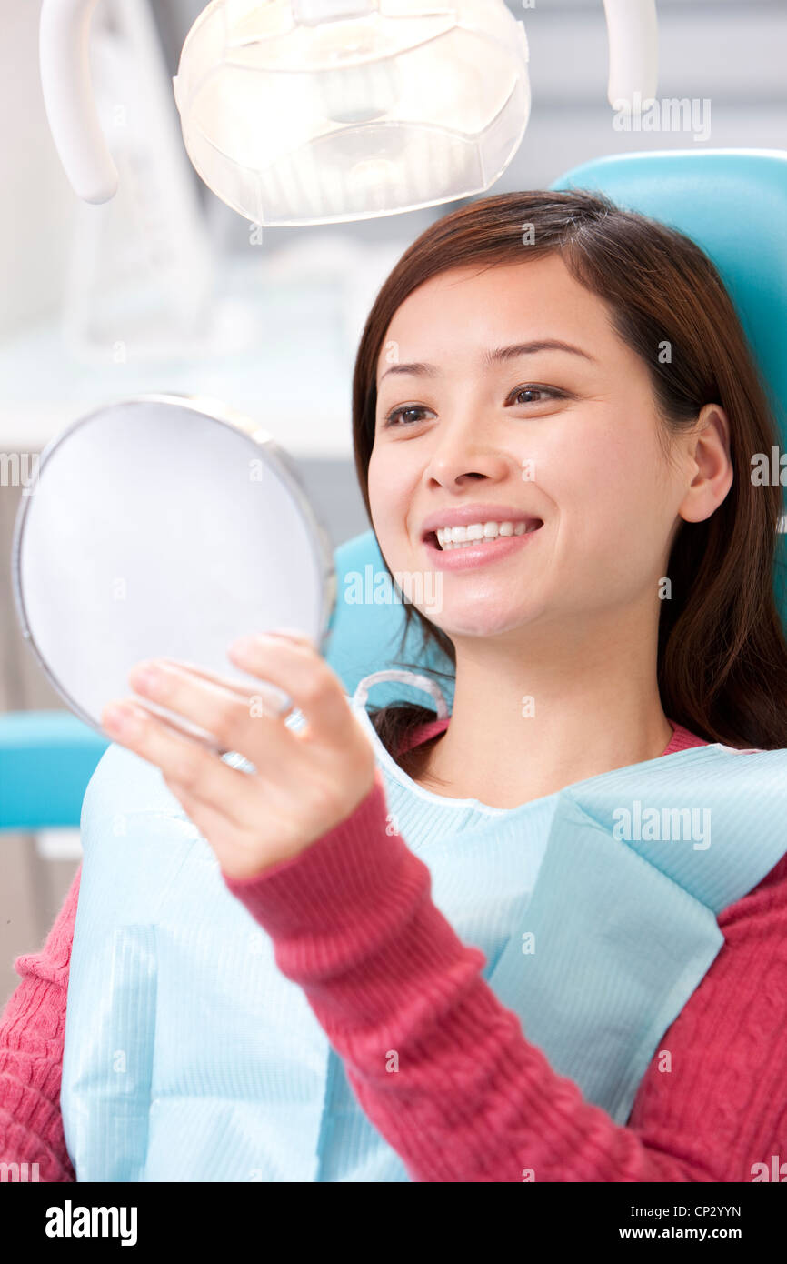 Patient examining teeth in mirror Stock Photo