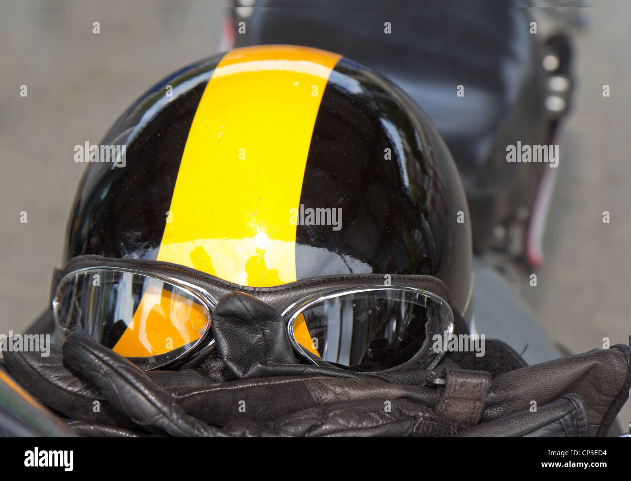 vintage safety gear for motorbikes and convertible cars consisting of leather gloves, helmet and pilot goggles on bike seat Stock Photo