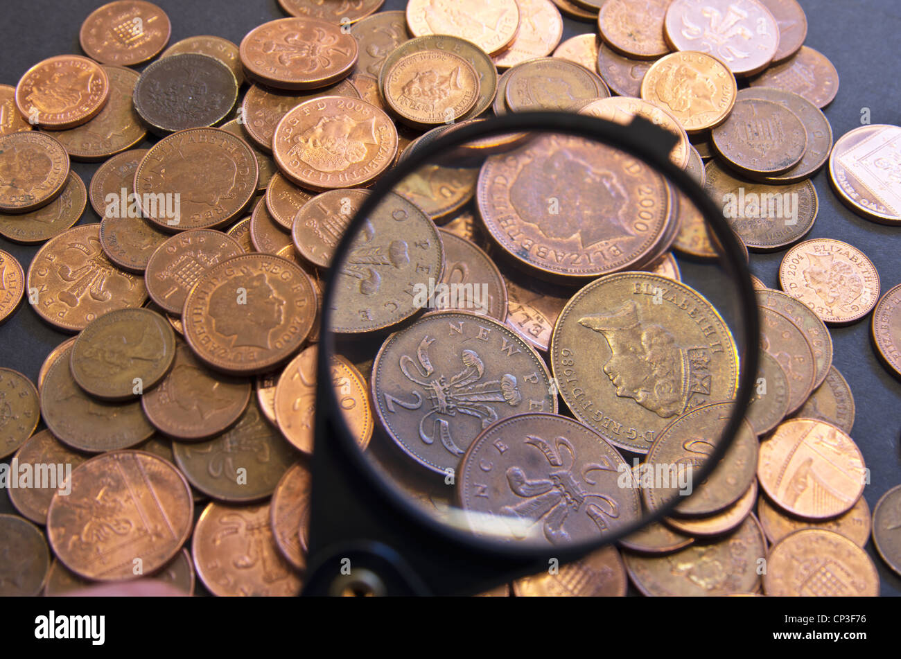 A mound of UK coins being inspected with a magnifying glass Stock Photo ...