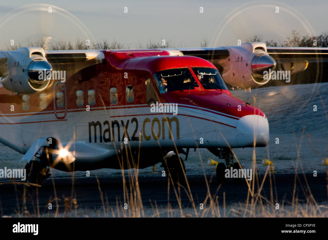 Propellor airliner turns at end of runway with prop discs shining in early morning sun Stock Photo