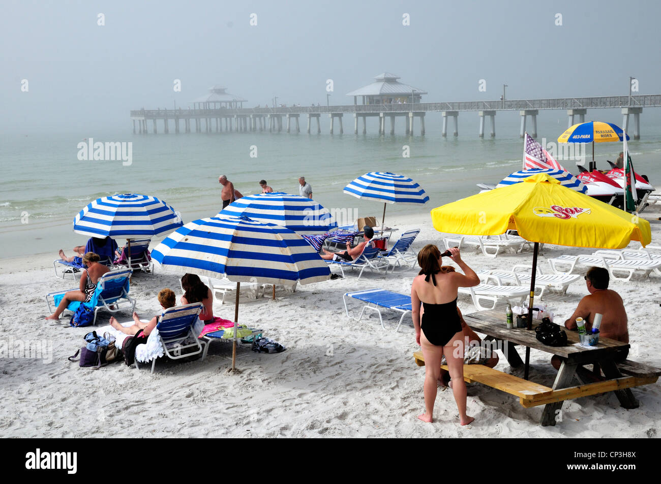 Vacationers at Fort Myers Beach, Florida, waiting for the fog to lift. The fishing pier is in the background Stock Photo