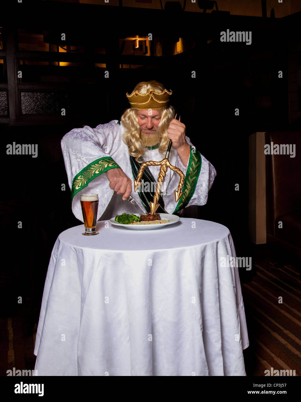 King Neptune enjoying a steak and beer in a restaurant. Stock Photo