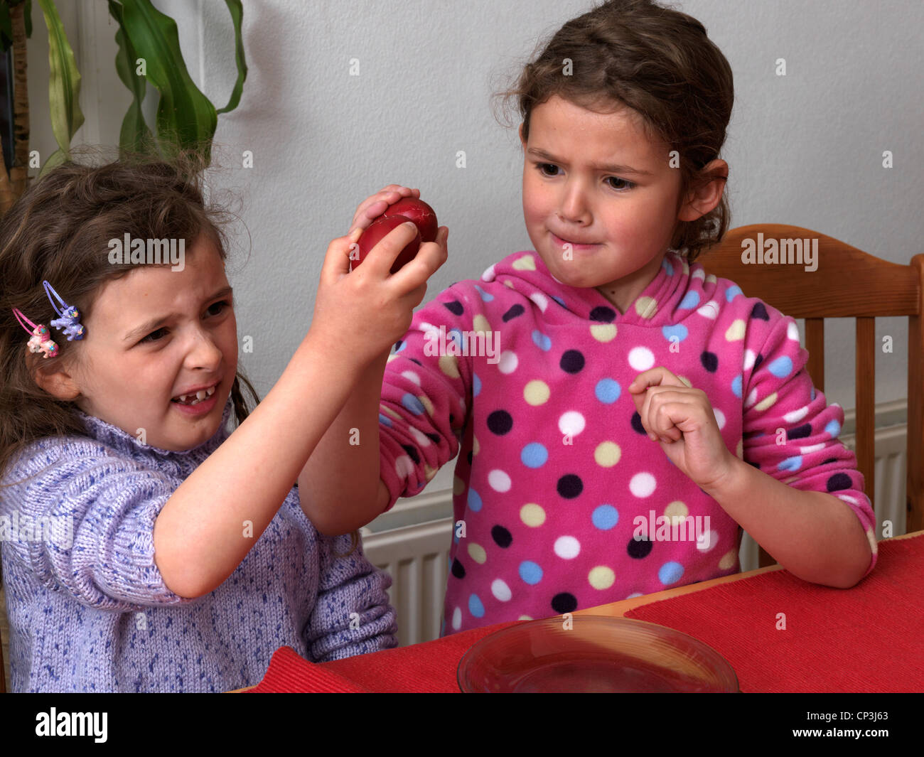 Sisters Cracking Red Hard Boiled Eggs at Easter Surrey England Stock