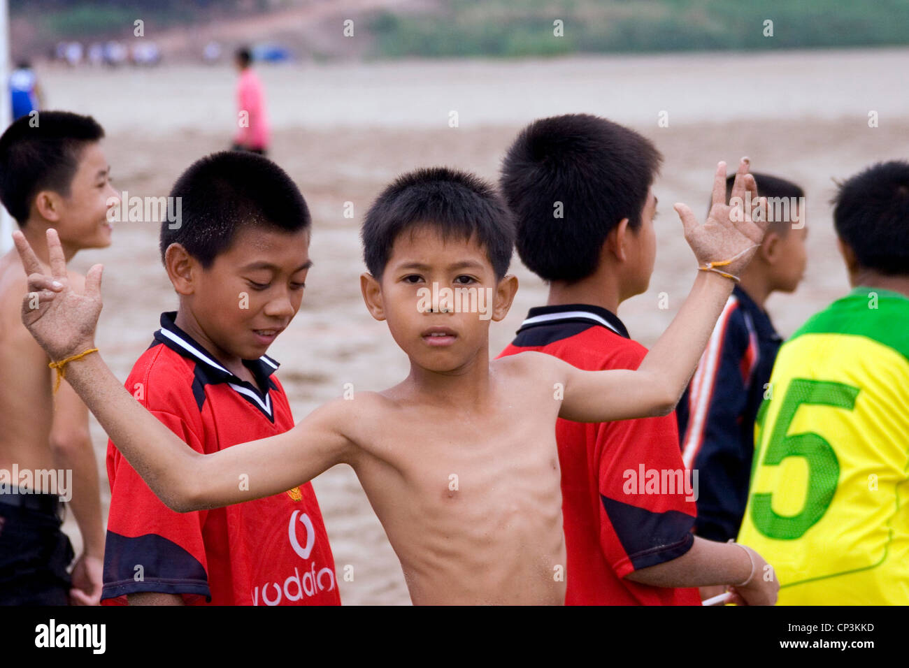 A young boy soccer (football) player is standing with team mates at a match at the Mekong River in Vientiane, Laos. Stock Photo