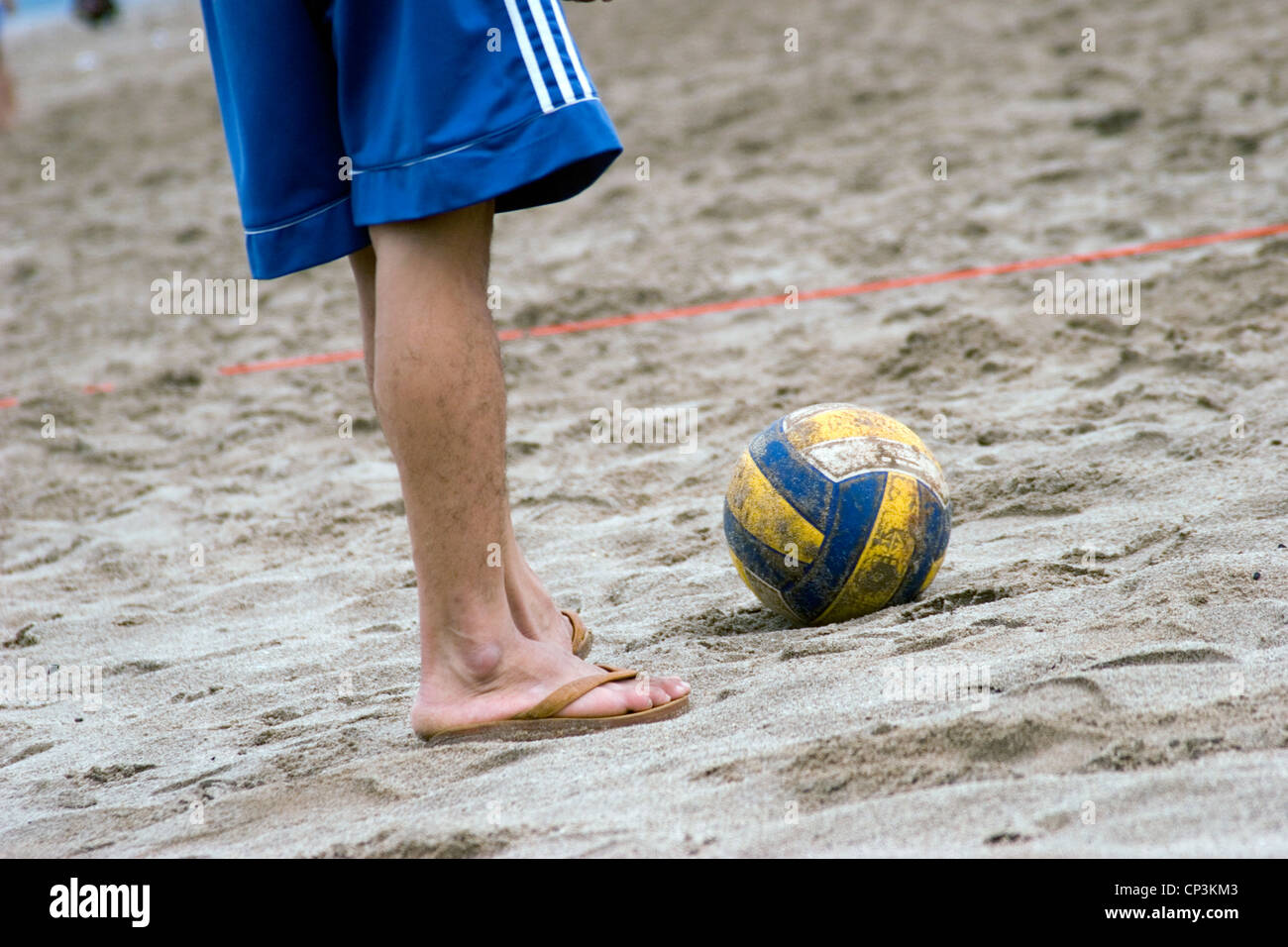 A teenage soccer player is wearing rubber sandals at a match on the sandy shore of the Mekong River in Vientiane, Laos. Stock Photo