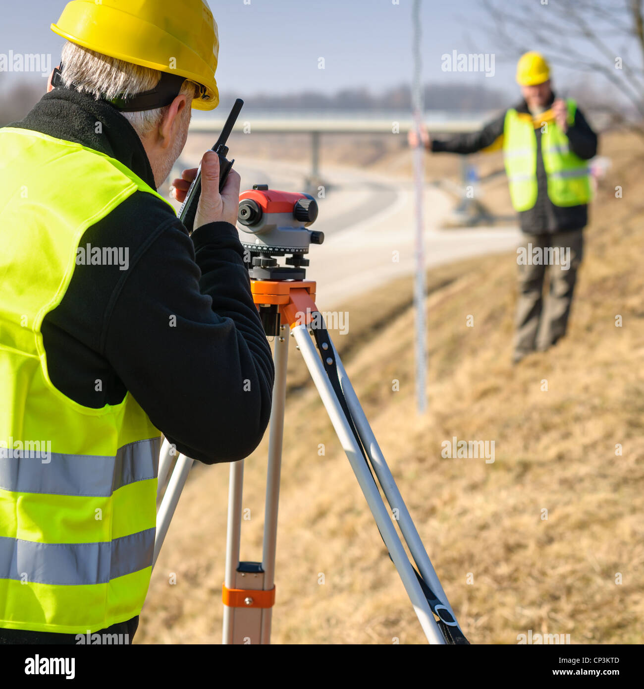Land surveyors on highway measuring with theodolite Stock Photo