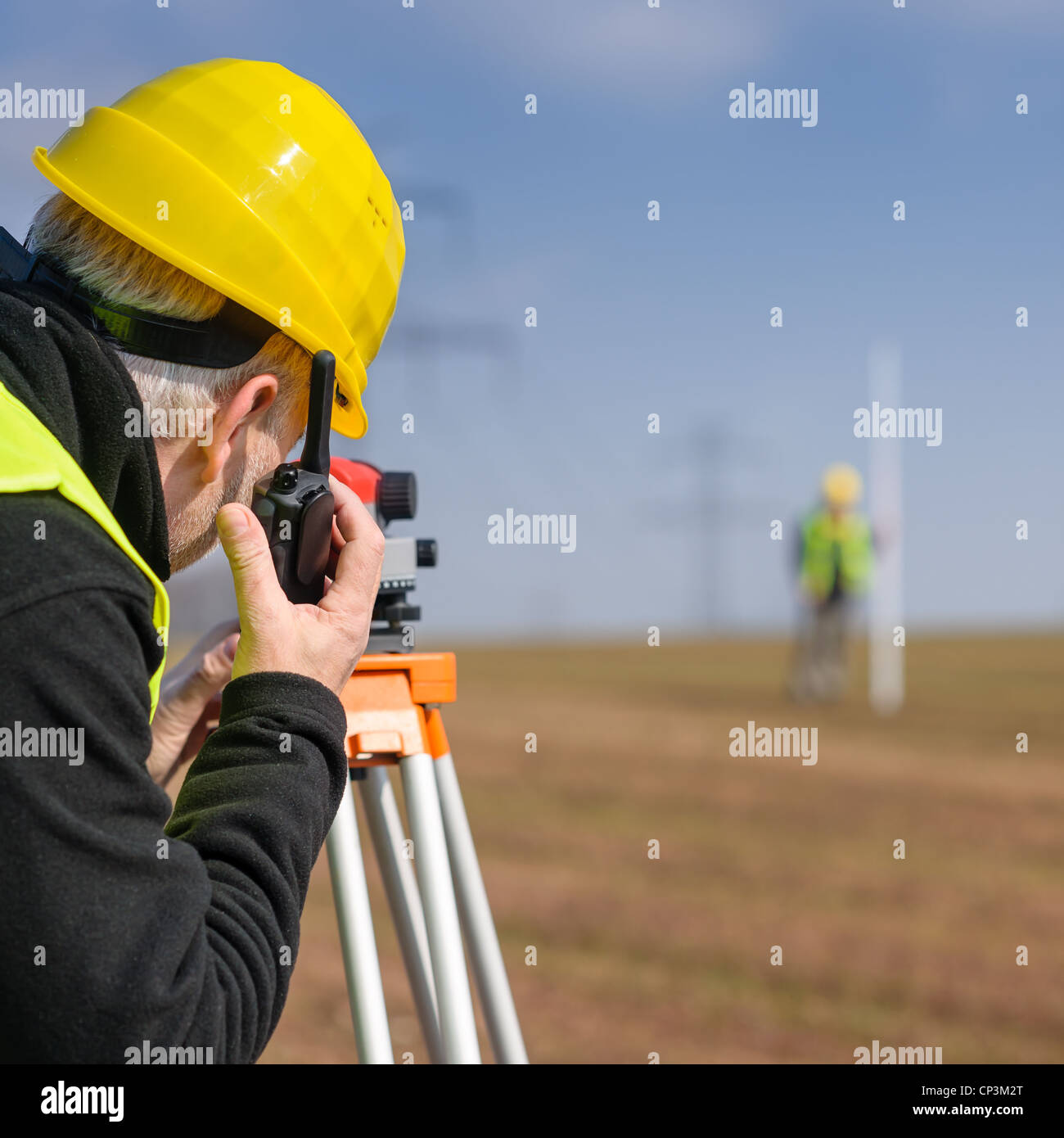 Land surveyors measuring land with tacheometer speaking through