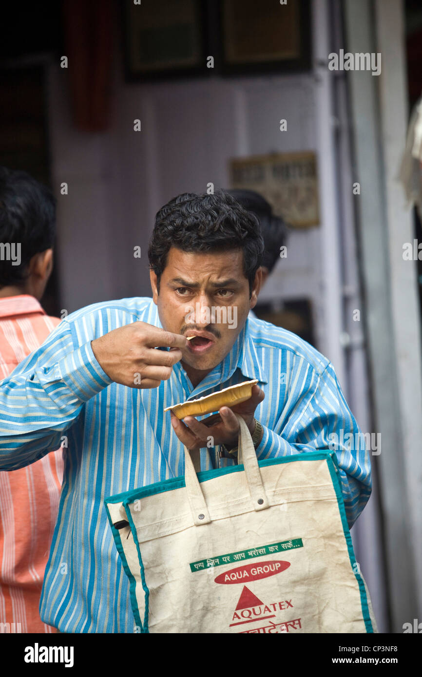 A man eats street food at the Ashok Chat Corner in Chawri Bazaar, Old Delhi India Stock Photo