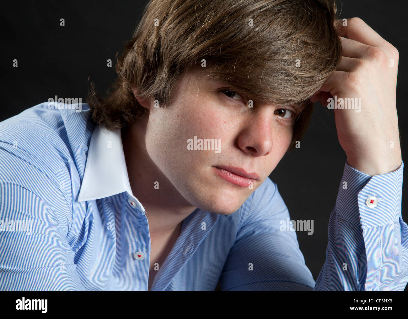 Colour headshot of male model wearing blue shirt photographed against black backdrop Stock Photo