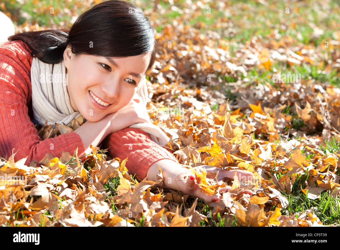 Young woman lying on the grass surrounded by Autumn leaves Stock Photo ...