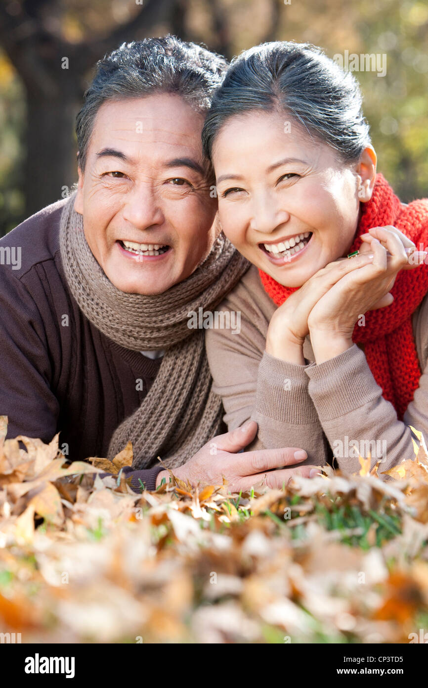 Senior couple lying on the grass surrounded by Autumn leaves Stock ...