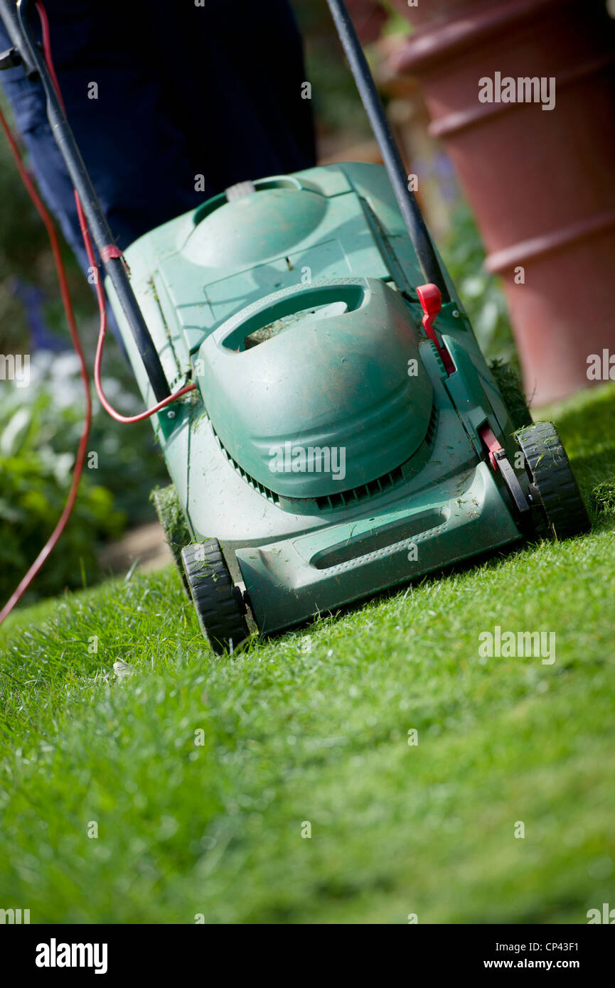 Gardener mowing the lawn in april. Cutting the grass. Gardening jobs Stock Photo