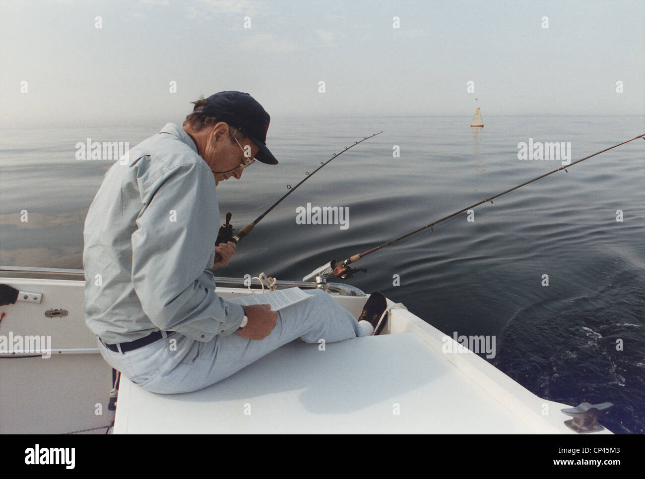 President George H.W. Bush reading a long memo as he fishes at his summer home in Kennebunkport Maine. Ca. 1990. Stock Photo