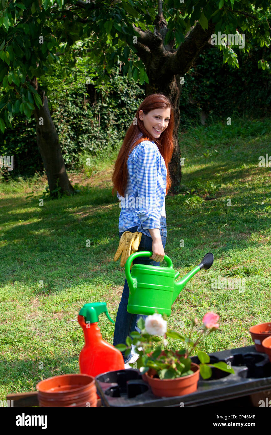 a woman with a watering can in garden Stock Photo - Alamy