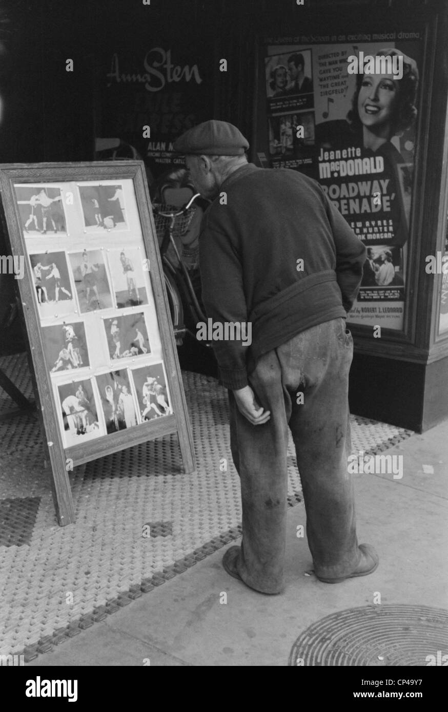 Elderly man with patches clothing looking at stills of Joe Lewis fight. Windsor Locks Connecticut. Oct. 1939. Stock Photo