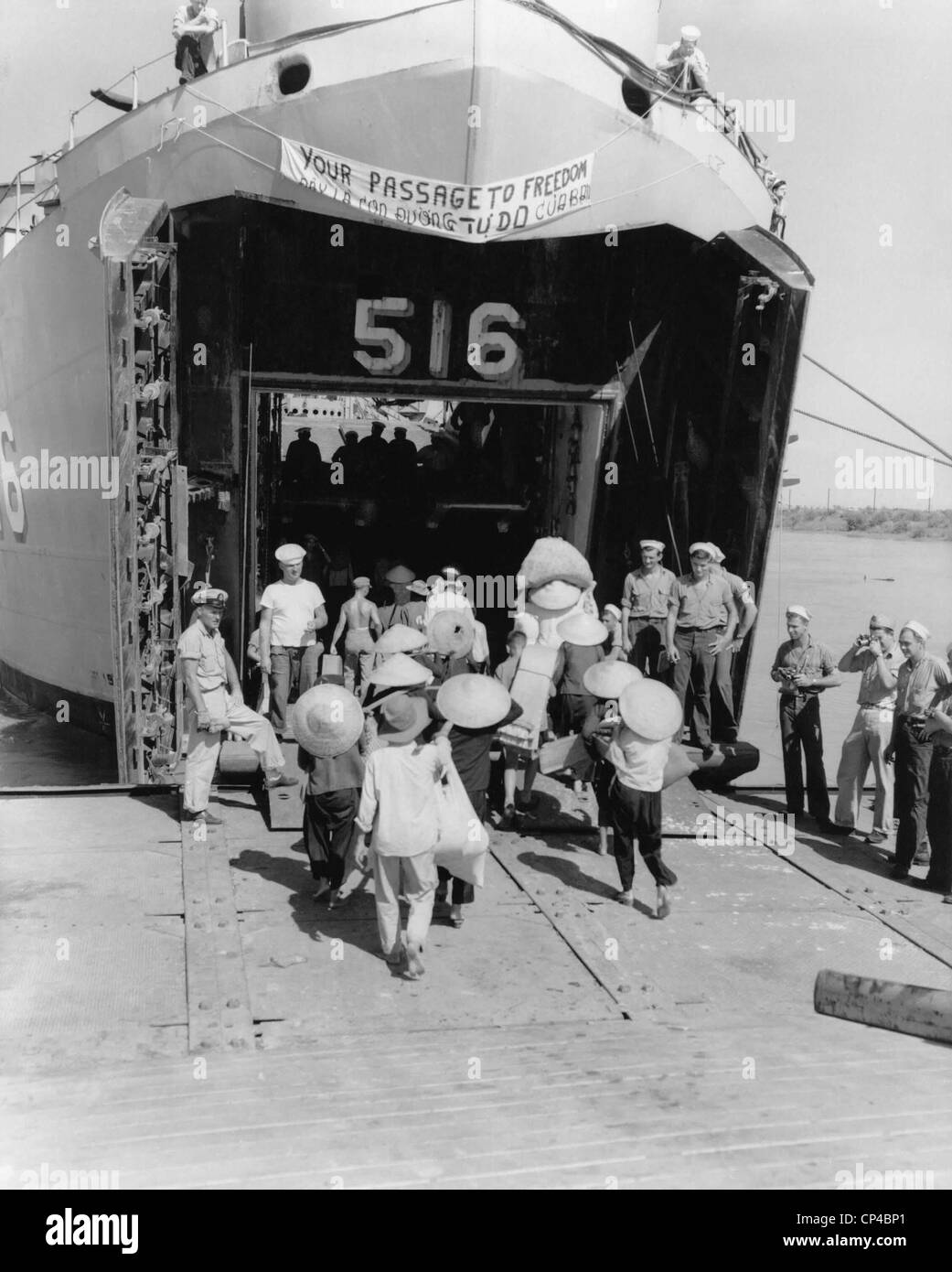 North Vietnamese refugees board an US ship bound for Saigon, South Vietnam. The ship bears a sign reading, YOUR PASSAGE TO Stock Photo