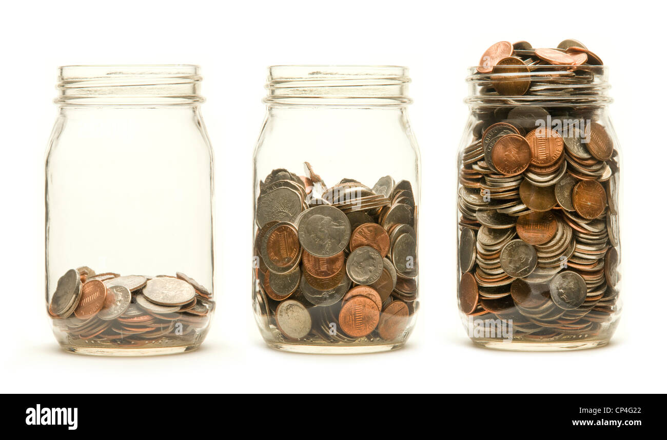 Increasing numbers of American coins in a three glass jars against a white background Stock Photo