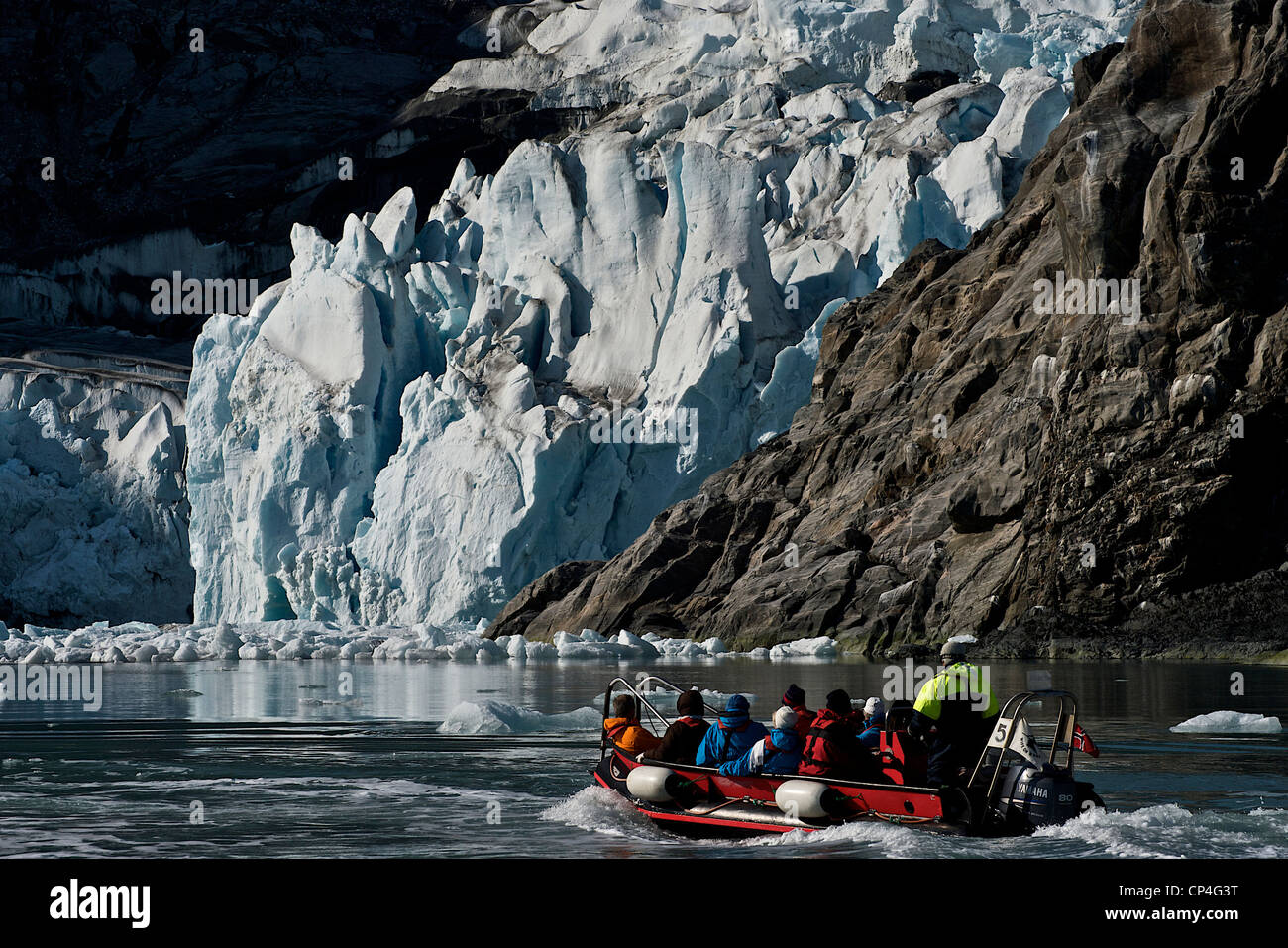 Greenland - West Coast. Tourists in excursion on a rubber boat watching rocks covered by ice. Stock Photo