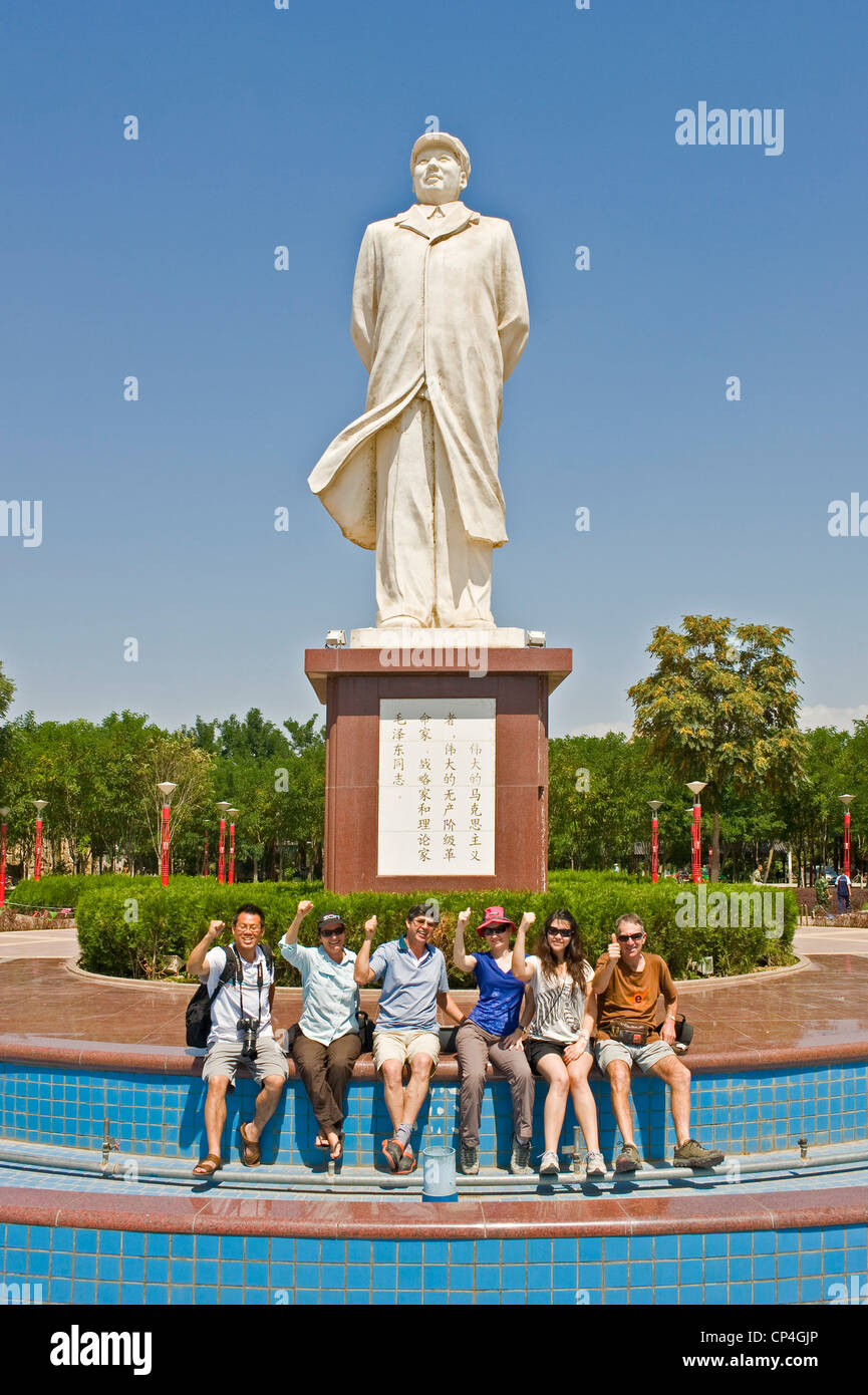 A european tourist group at the statue of Chairman Mao Zedong at a park near the Gao Miou temple complex in Zhongwei. Stock Photo