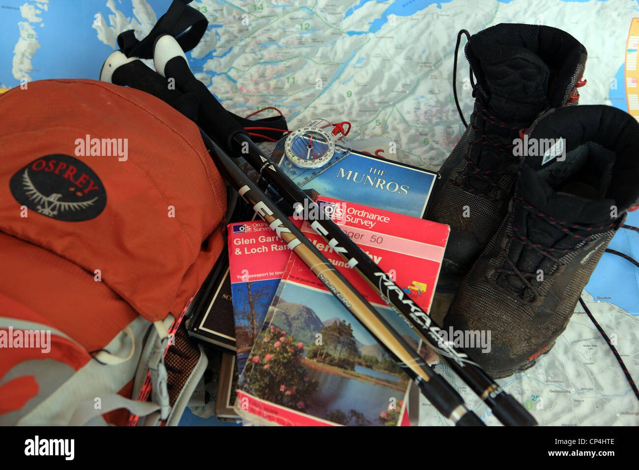 Hillwalking gear, including books, OS maps, walking poles, boots & rucksack, on a map of Scotland Stock Photo
