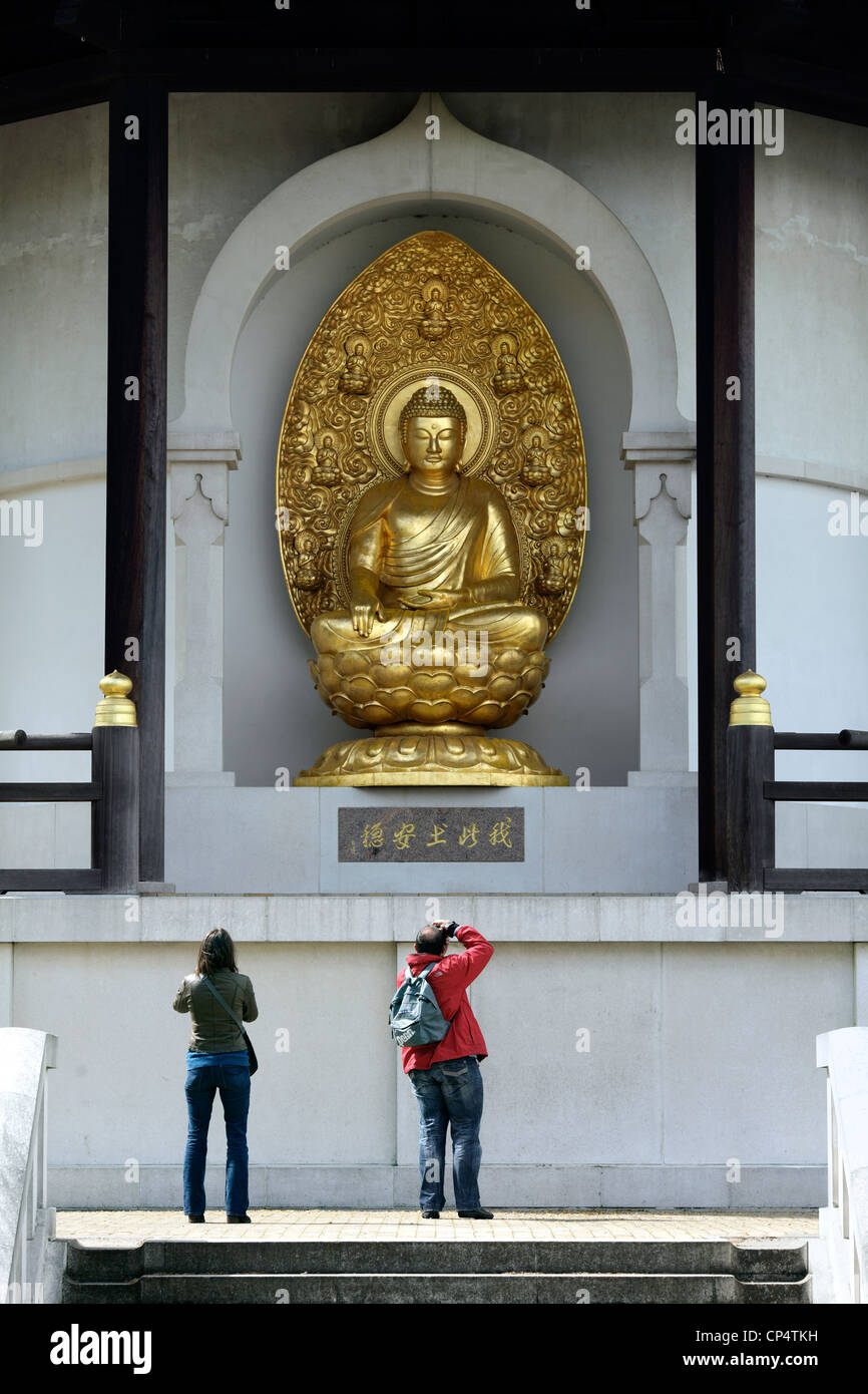 People photographing a gilded bronze sculpture of the Buddha at the Peace Pagoda, Battersea Park, London. Stock Photo