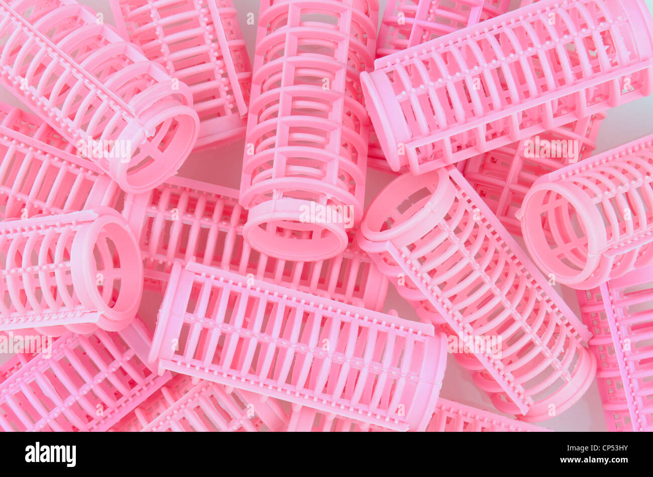 Plastic pink hair curlers in a random pattern that fills the frame. Stock Photo
