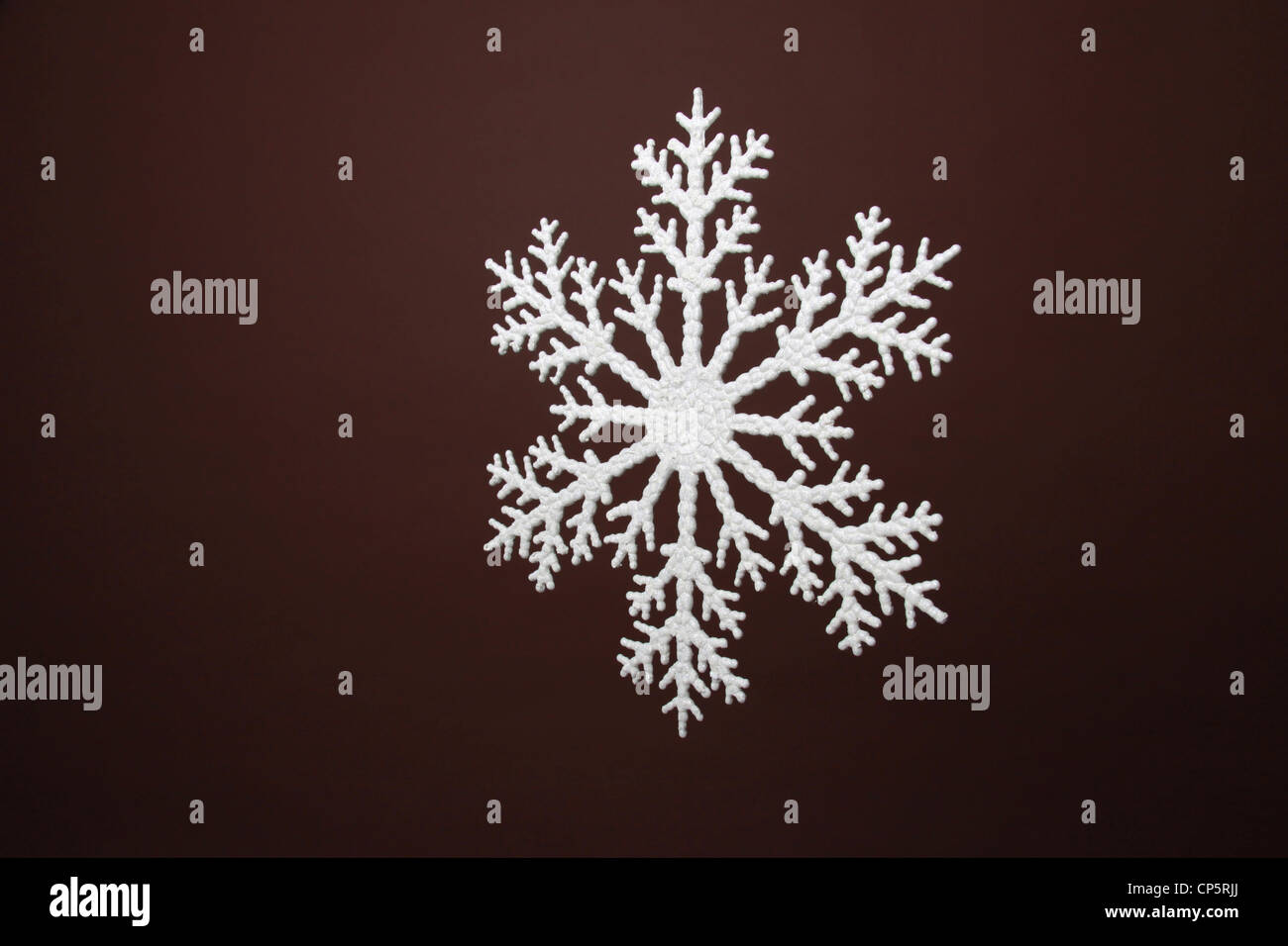 plastic sparkle white snowflake on brown background in studio Stock Photo