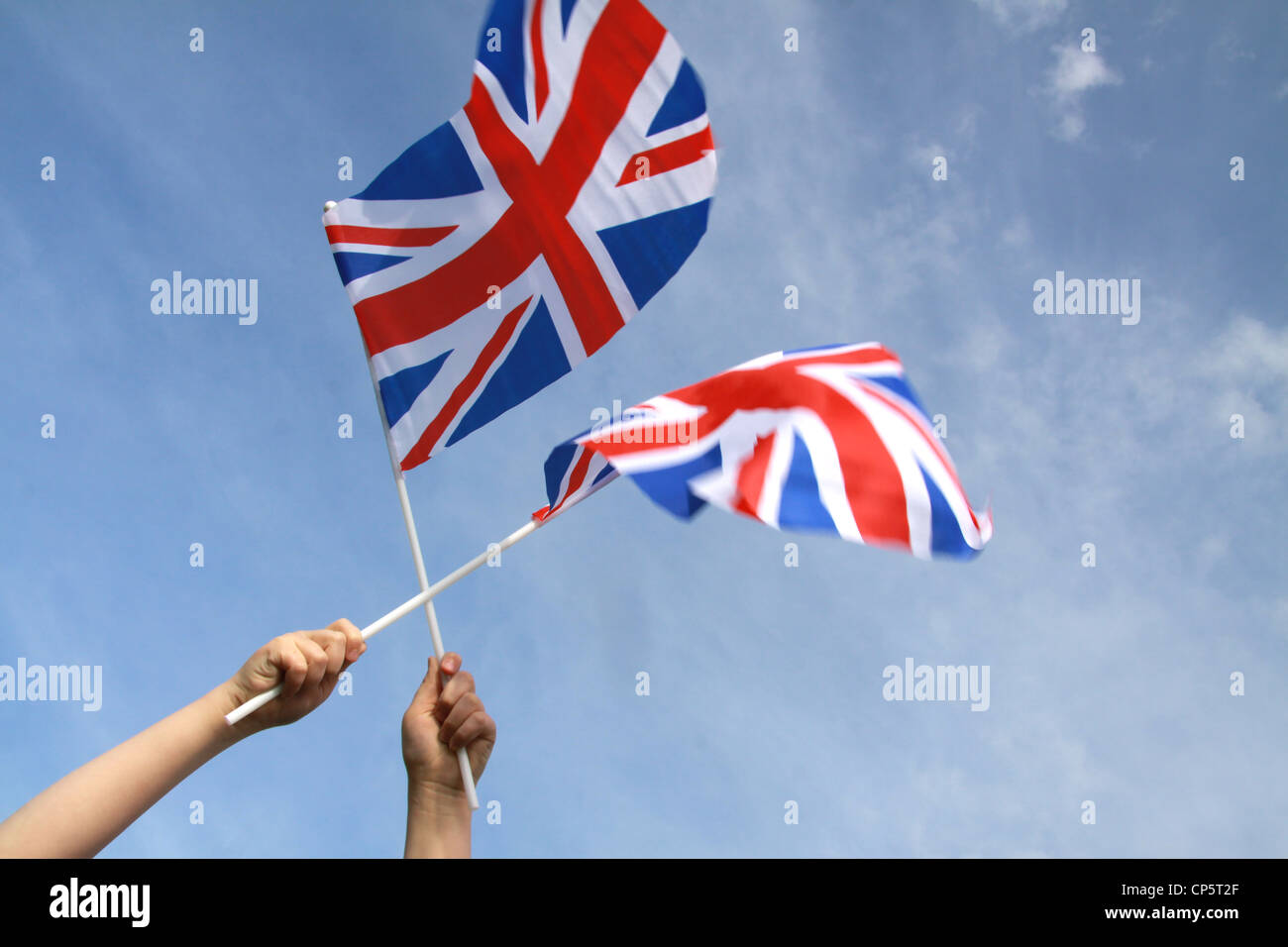 Jubilee United kingdom flags blowing in wind with blue sky with holding hands visible aiming for the sky Stock Photo