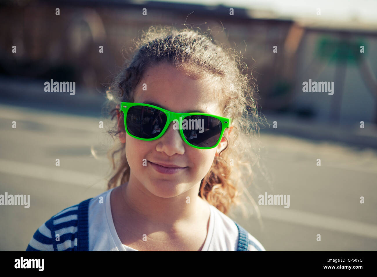 Young town girl wearing acid green wayfarer sunglasses and smiling to the camera Stock Photo