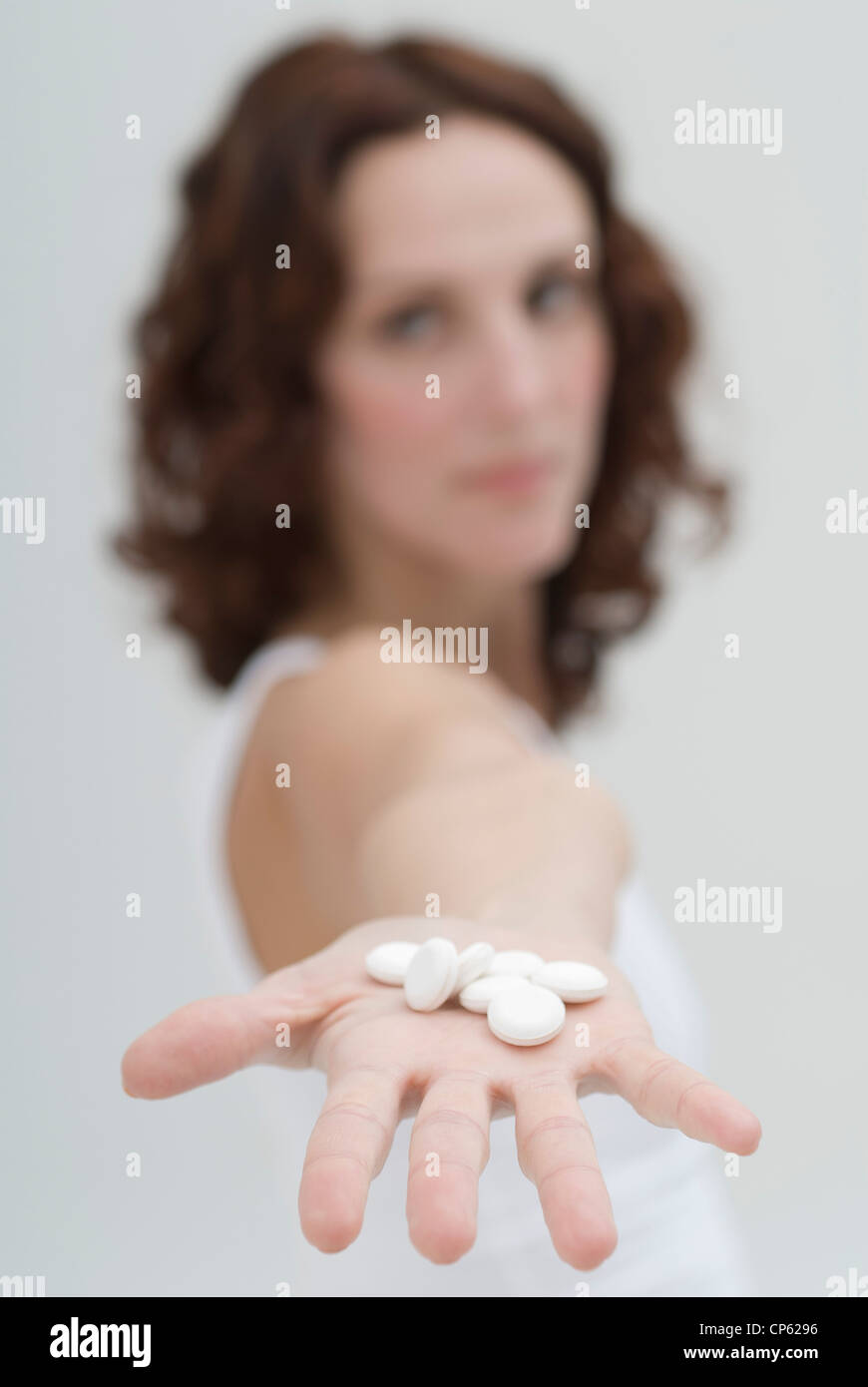 Mid adult woman showing white pills in hand Stock Photo