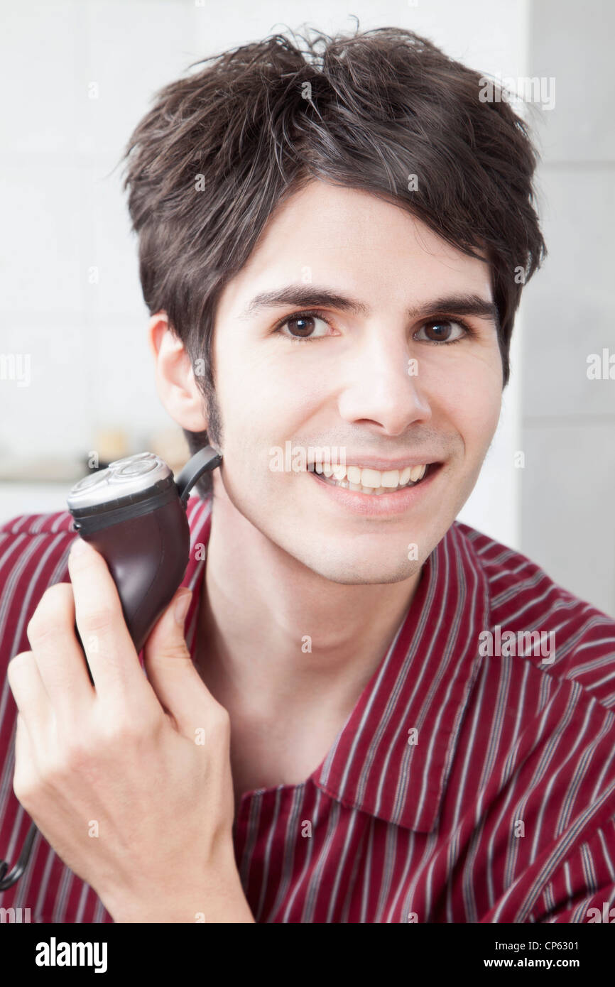 Young man doing shaving with electric razor, portrait Stock Photo Alamy