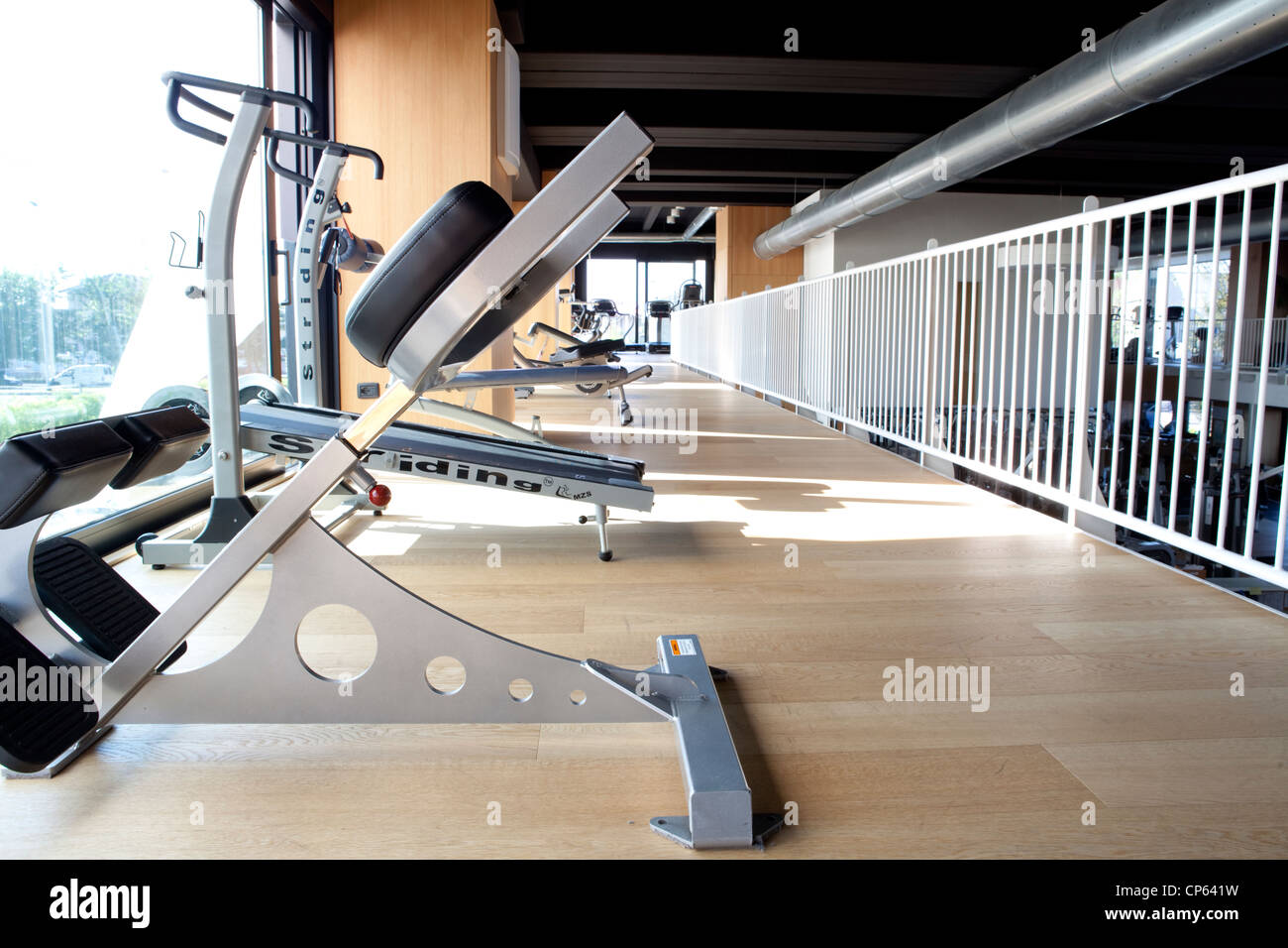 Gym muscle weight machine on hardwood floor by the window Stock Photo