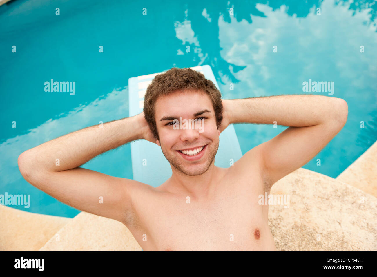 Spain, Mallorca, Young man lying on diving board, smiling, portrait Stock Photo