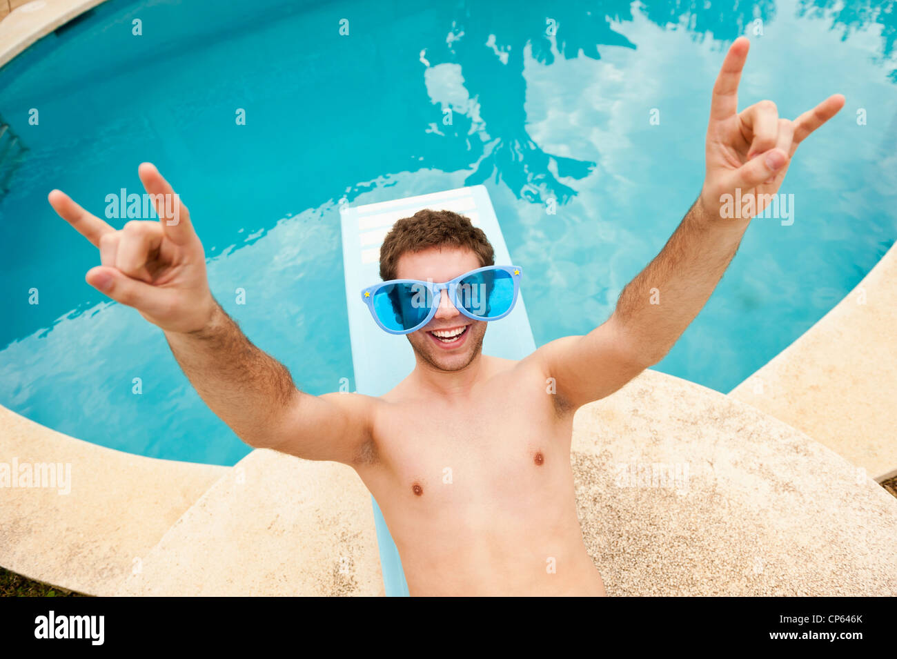 Spain, Mallorca, Young man with funny glasses on diving board, smiling Stock Photo