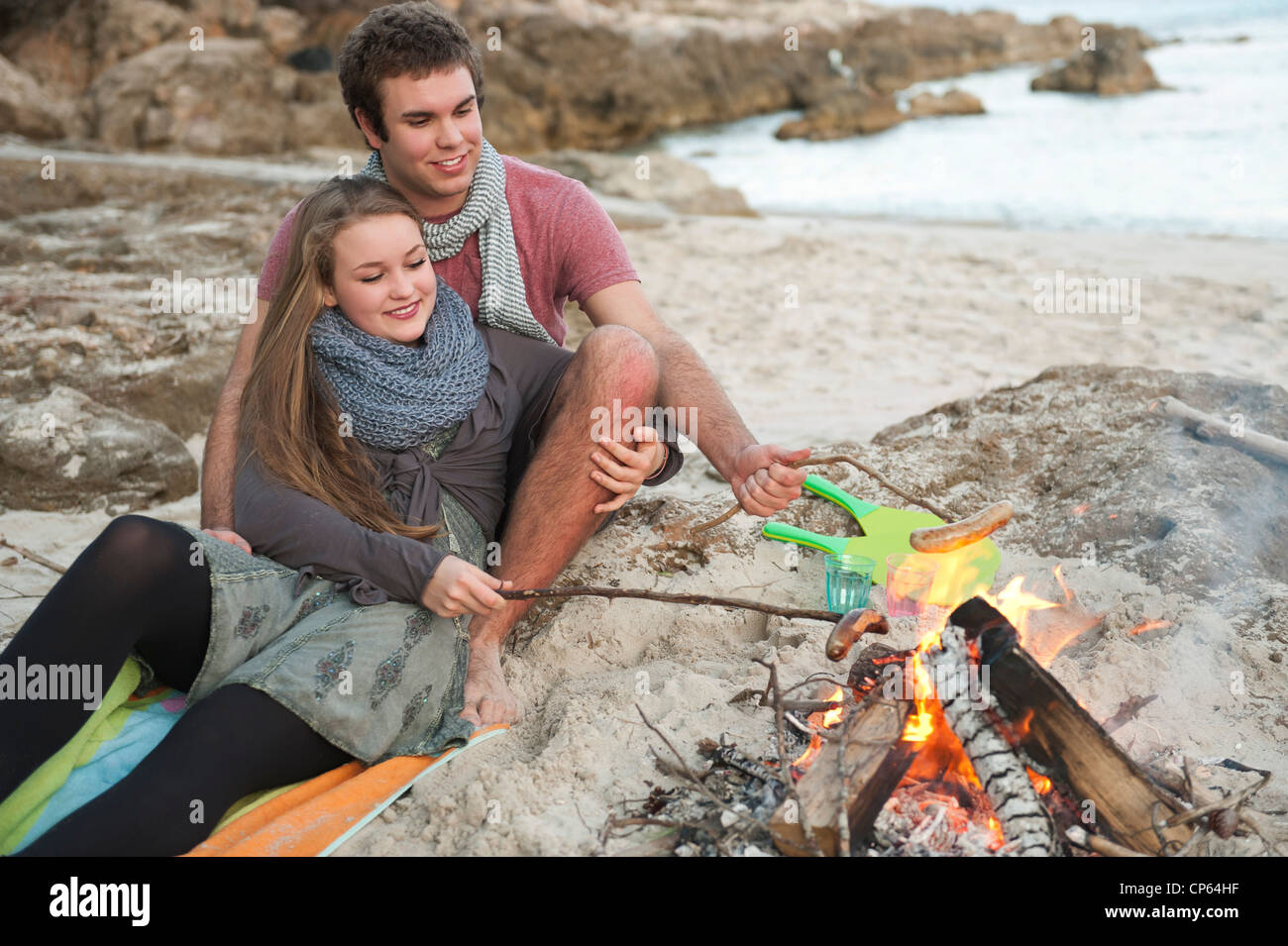 Spain, Mallorca, Couple preparing sausages on beach, smiling Stock Photo