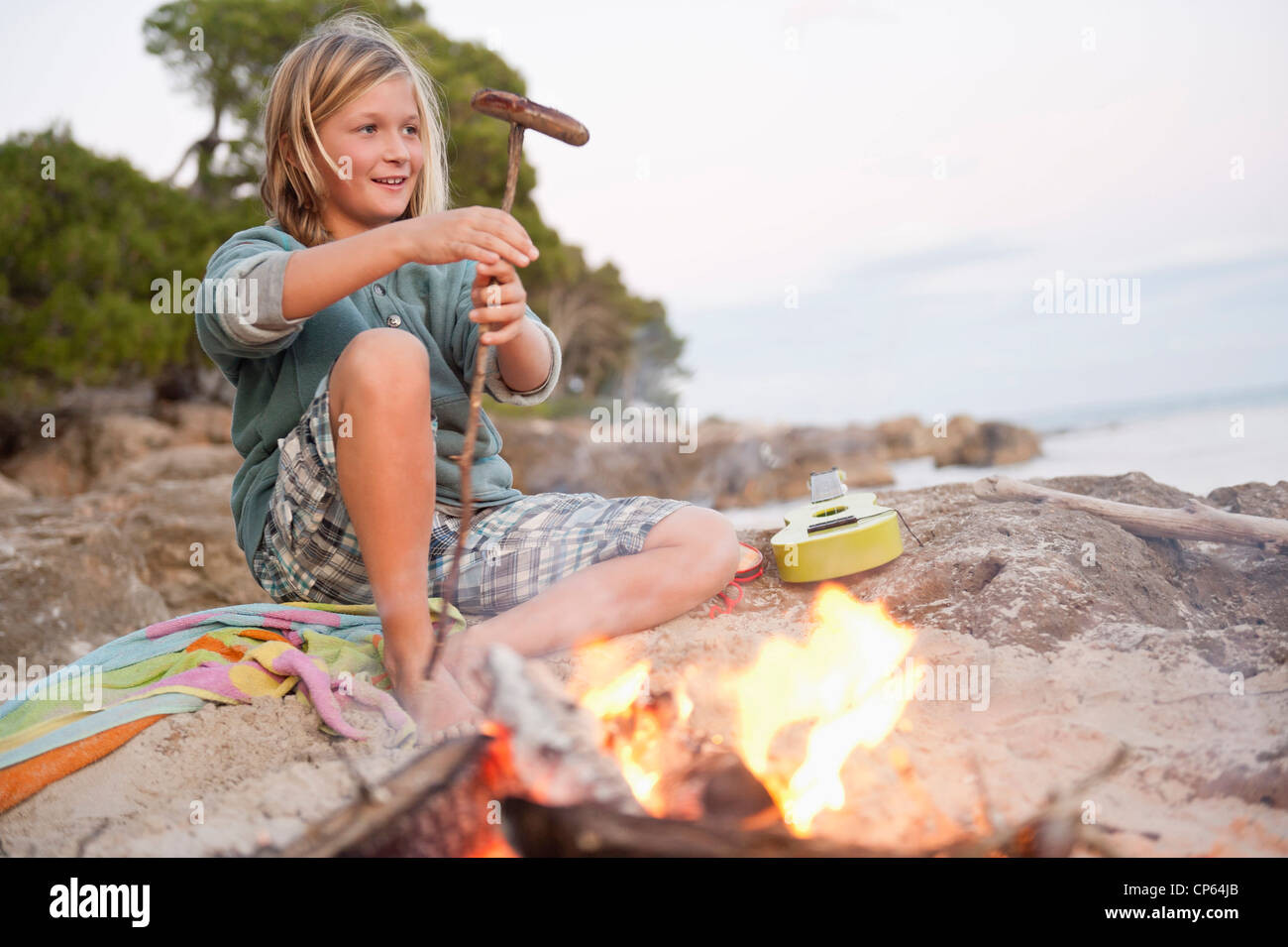 Spain, Mallorca, Boy barbecueing sausage on beach, smiling, portrait Stock Photo