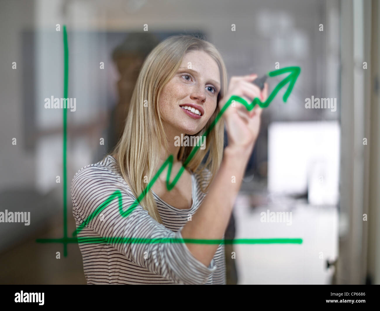 Germany, Cologne, Young woman drawing graph on glass Stock Photo
