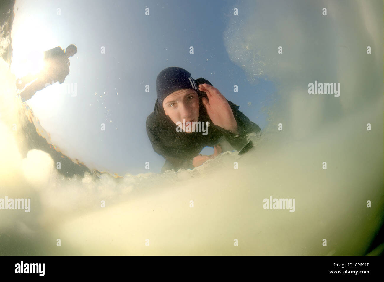 Diver looking into an ice hole, subglacial diving, ice diving, in the