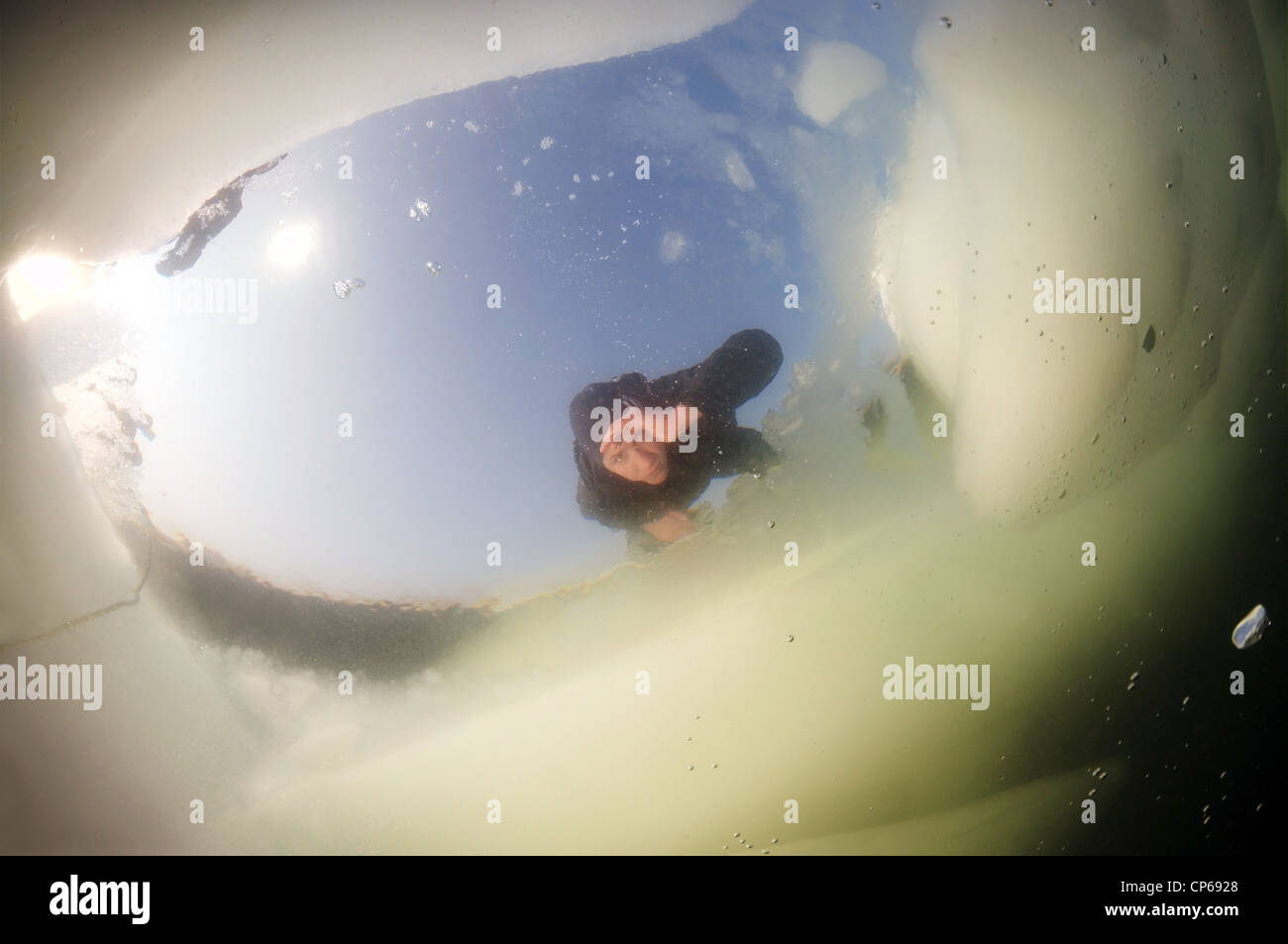 Diver looking into an ice hole, subglacial diving, ice diving, in the
