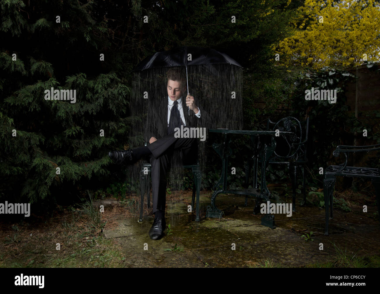 A business man being rained on by an umbrella, feeling 'under' the ...