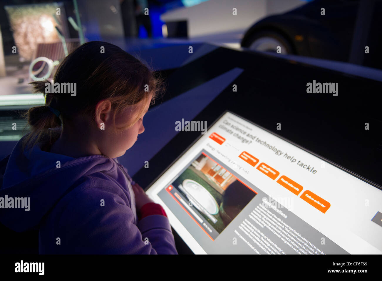 A young girl reading an interactive exhibit on climate change in the Science Museum in London. Stock Photo