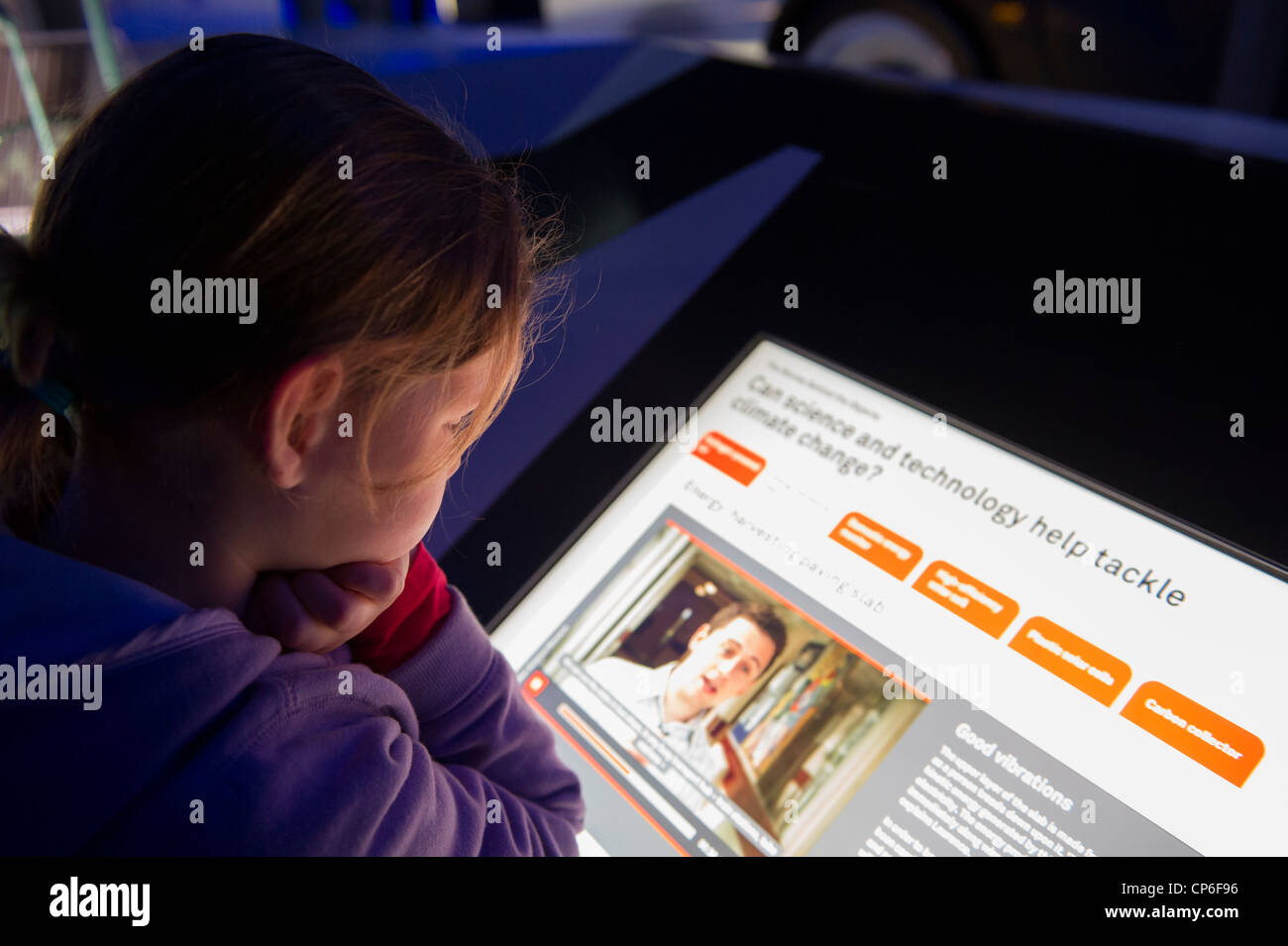 A young girl reading an interactive exhibit on climate change in the Science Museum in London. Stock Photo