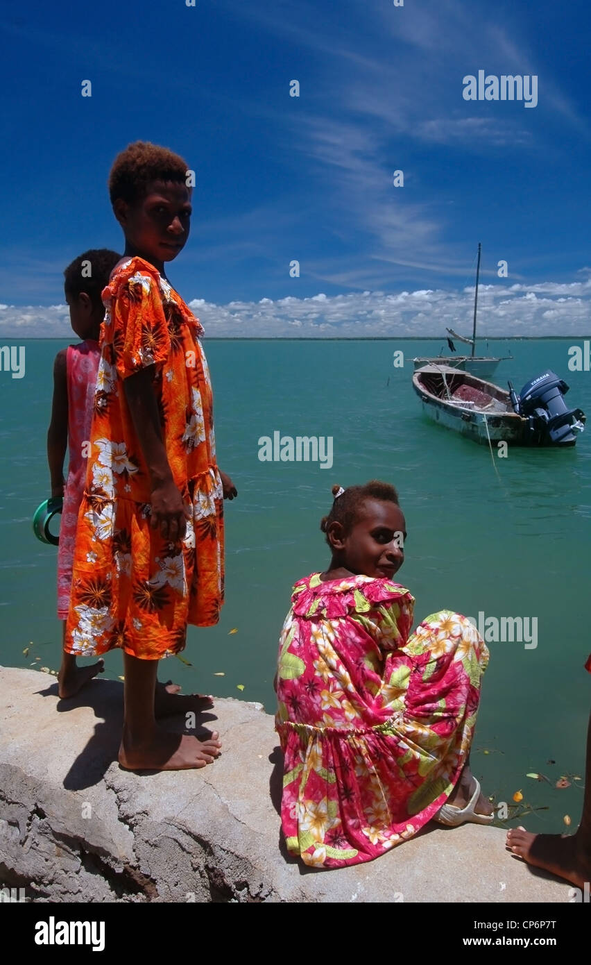 Kids on seawall watching king tide come in, Saibai Island, northern Torres Strait, Queensland, Australia. New Guinea on horizon. Stock Photo