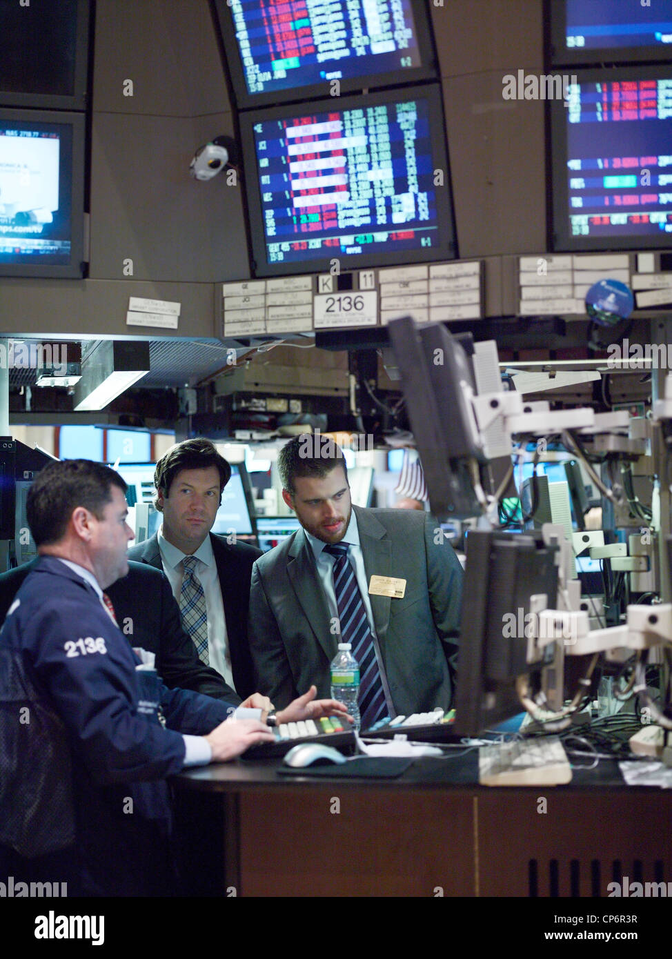 Businessmen watch a trader on the floor of the New York Stock Exchange Stock Photo