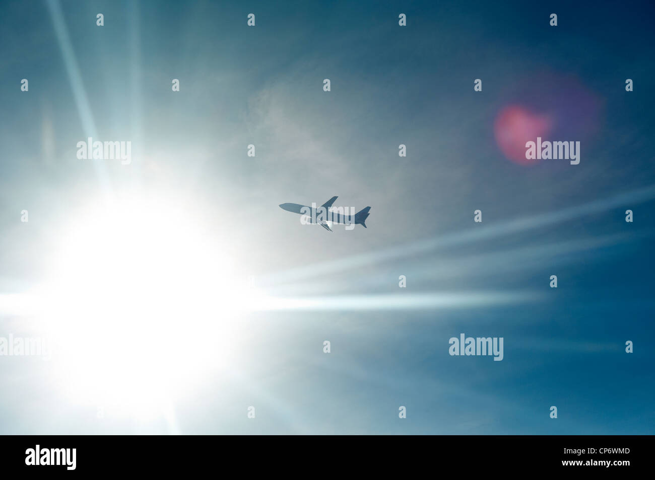 An airplane backlit by the sun in midair Stock Photo