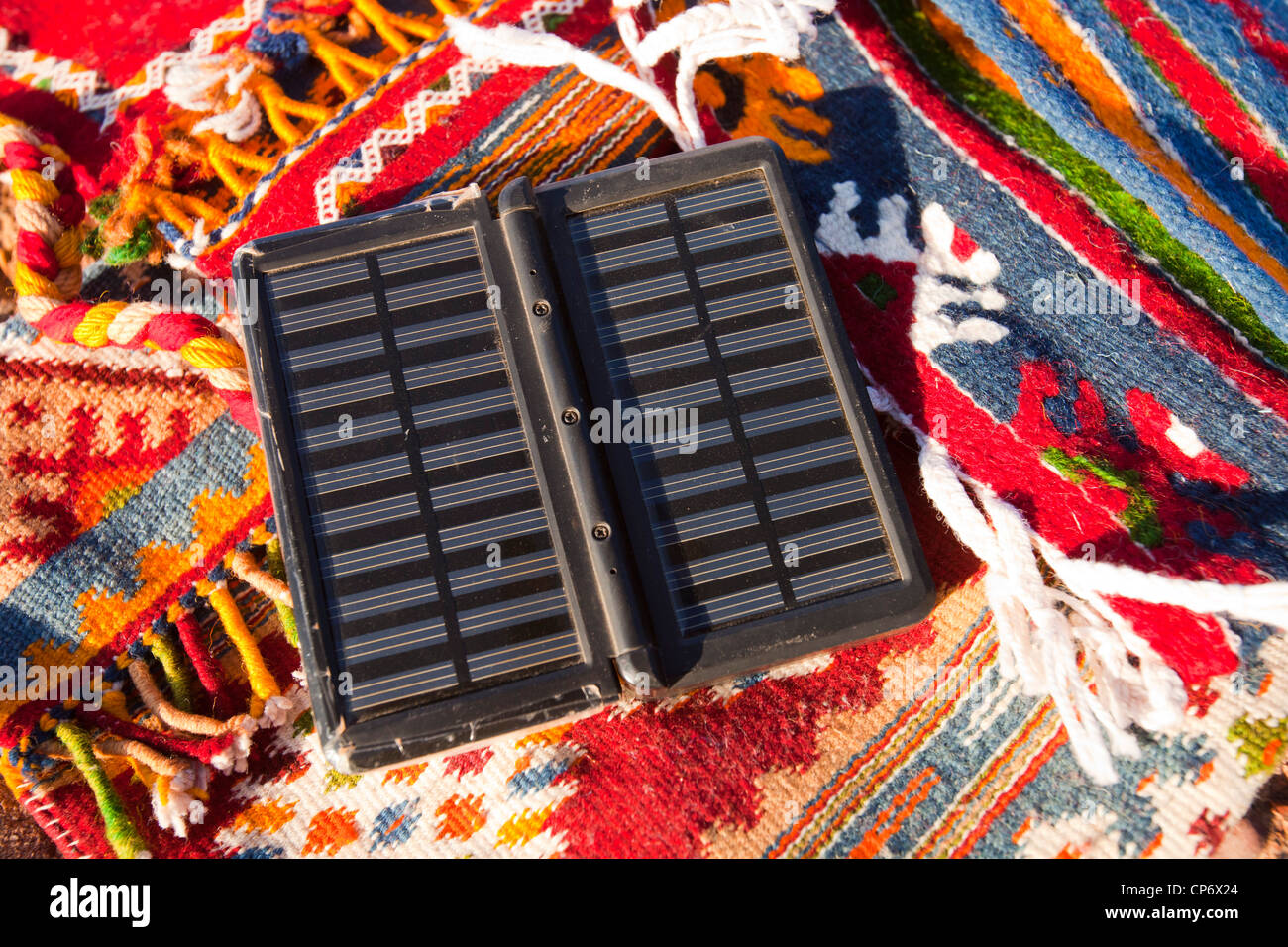 Berber Moroccan woven cloth rugs and bags in the Anti Atlas mountains of Morocco, North Africa, with a solar charger. Stock Photo